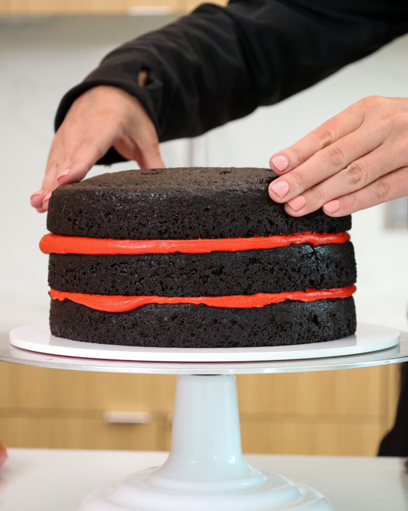 image of dark chocolate cake layers being stacked with red buttercream