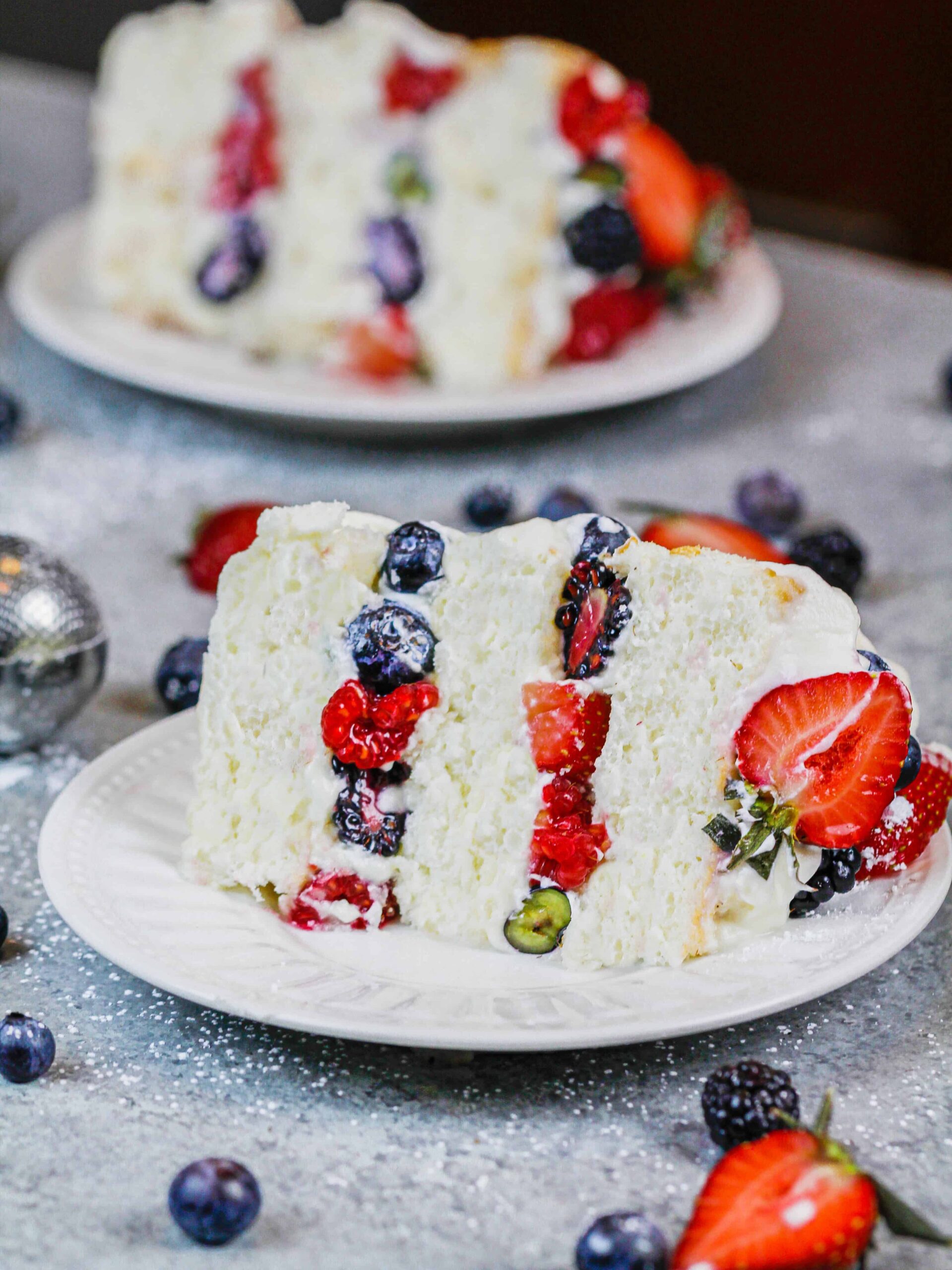 image of a slice of layered angel food cake filling with fresh berries and whipped cream frosting