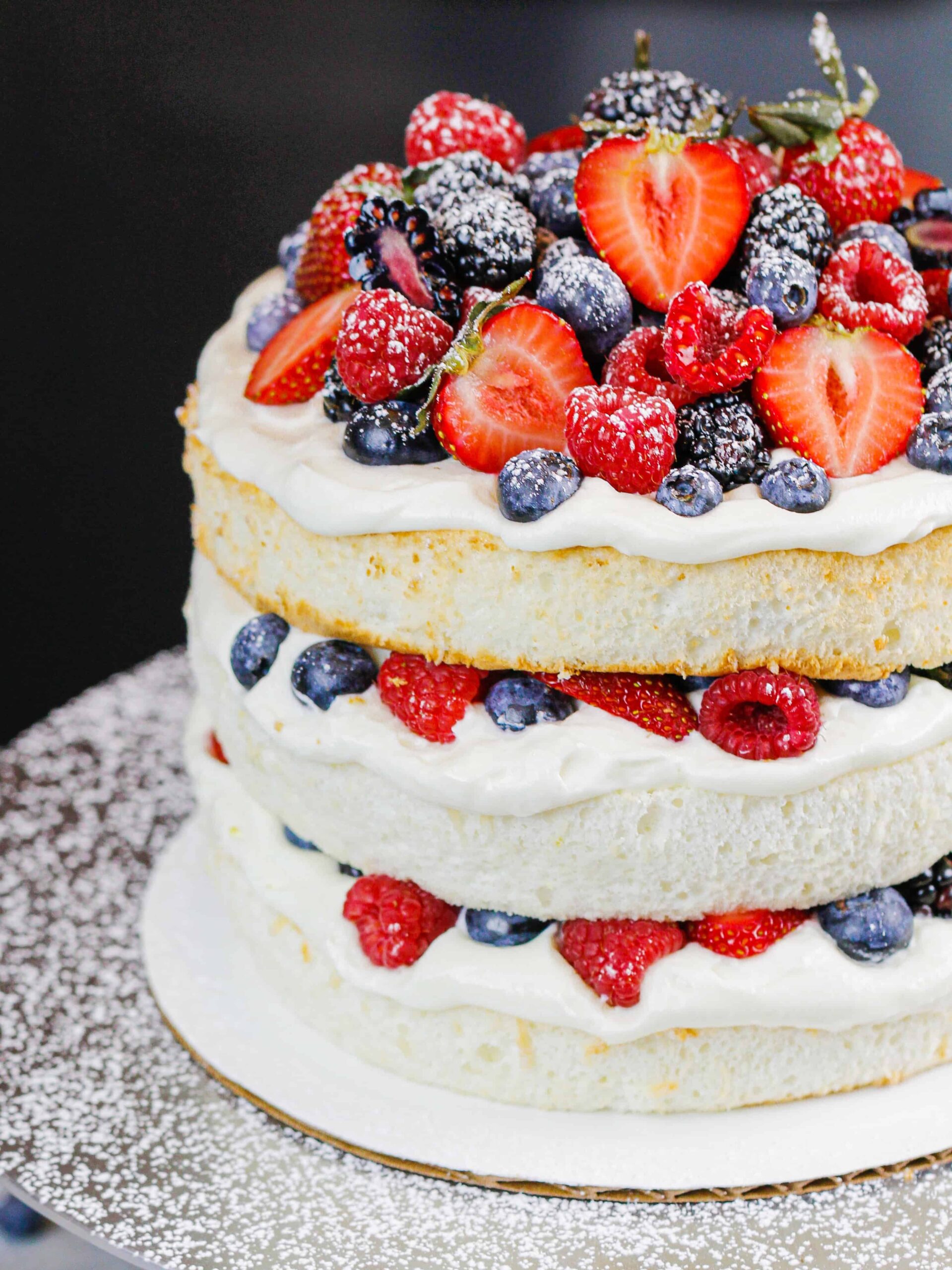 image of a layered angel food cake decorated with fresh berries and dusted with powdered sugar