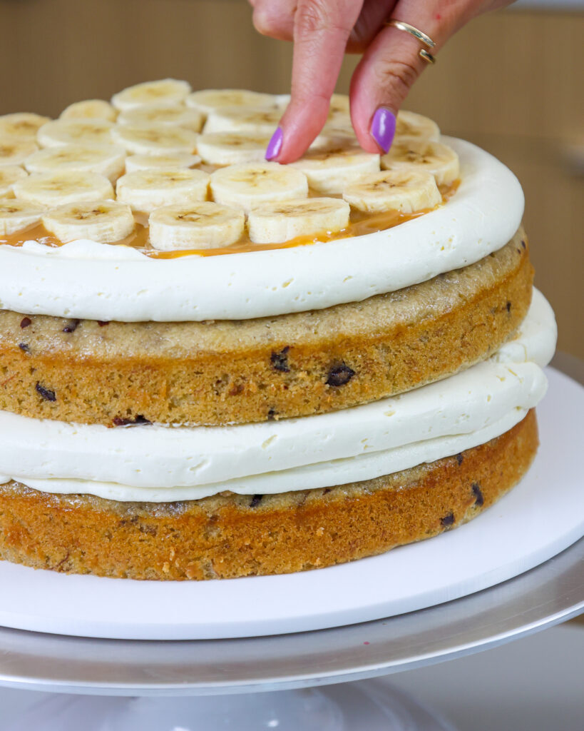 image of a banana cake being filled with toffee and fresh banana slices