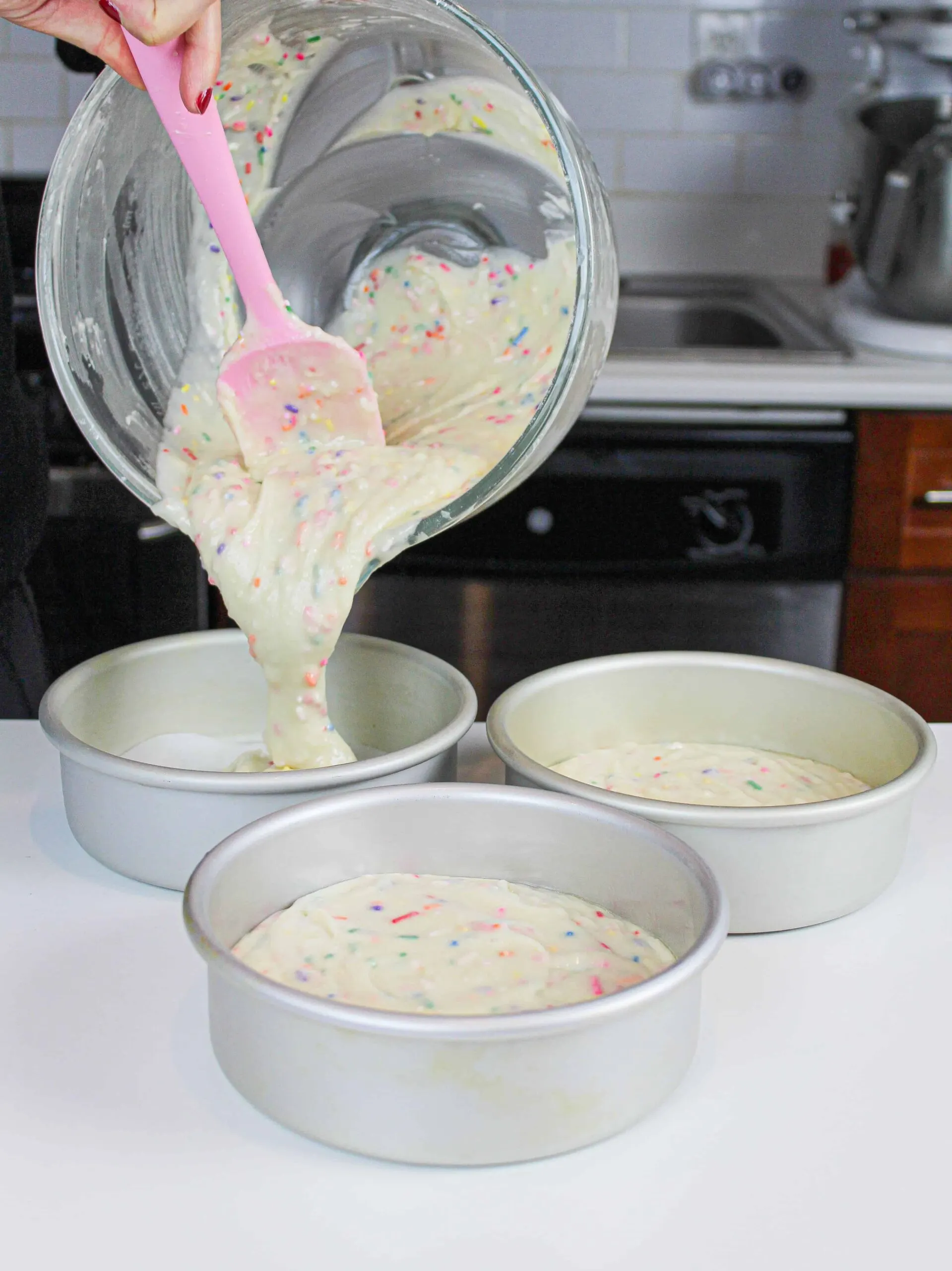 image of pouring funfetti cake batter in three, 6-inch cake pans