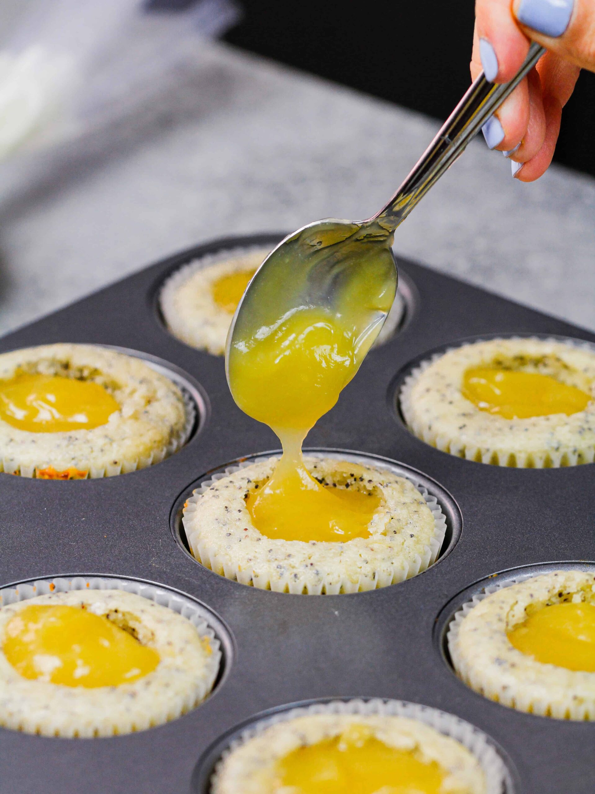 image of lemon curd being added as a filling to lemon poppy seed cupcakes