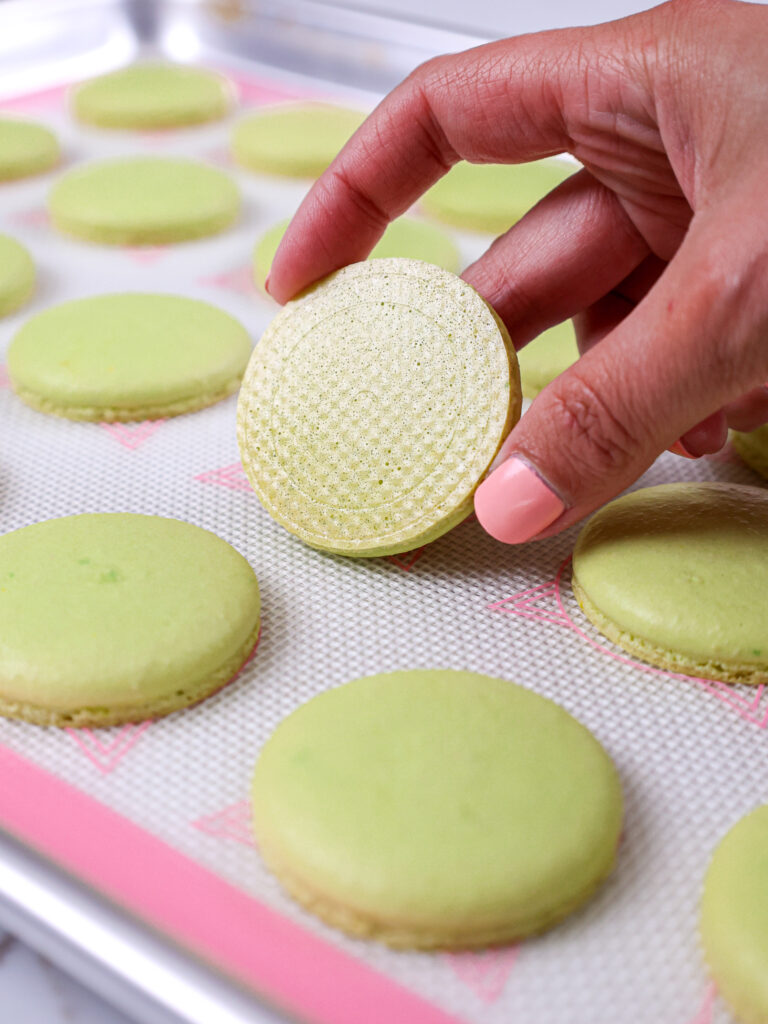 image of green macaron shells that have been properly baked and have smooth, shiny bottoms
