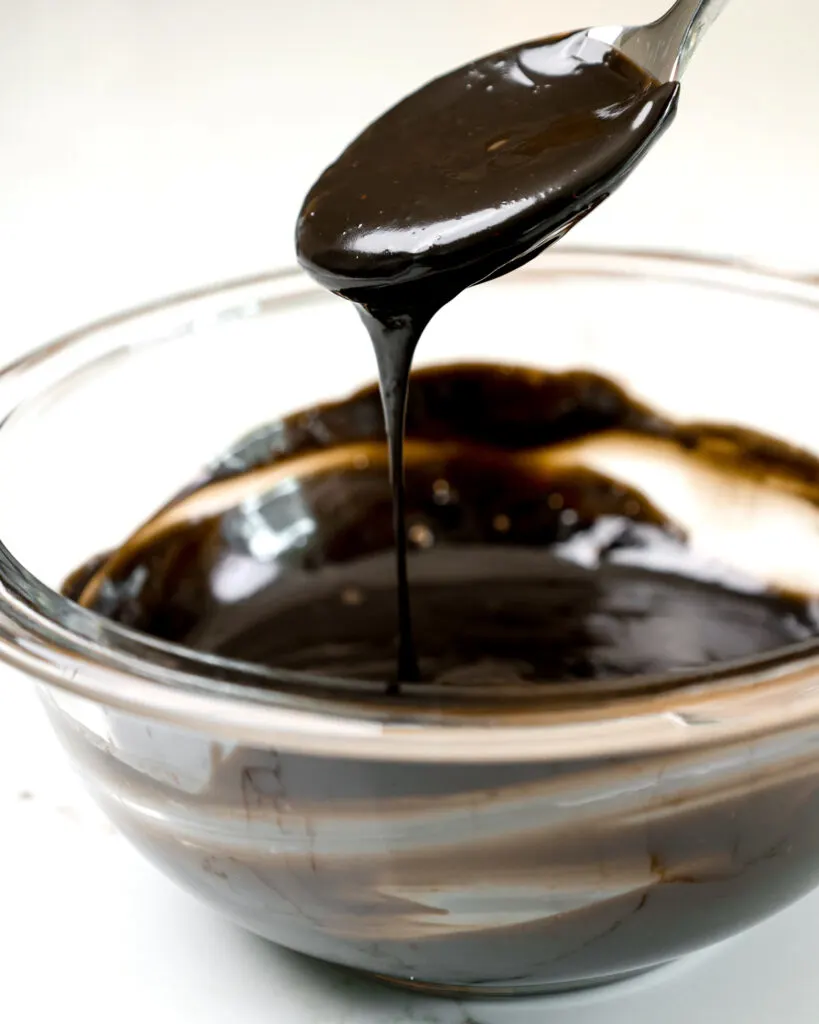 image of black dark chocolate ganache that's been mixed and is ready to use to add drips around a cake