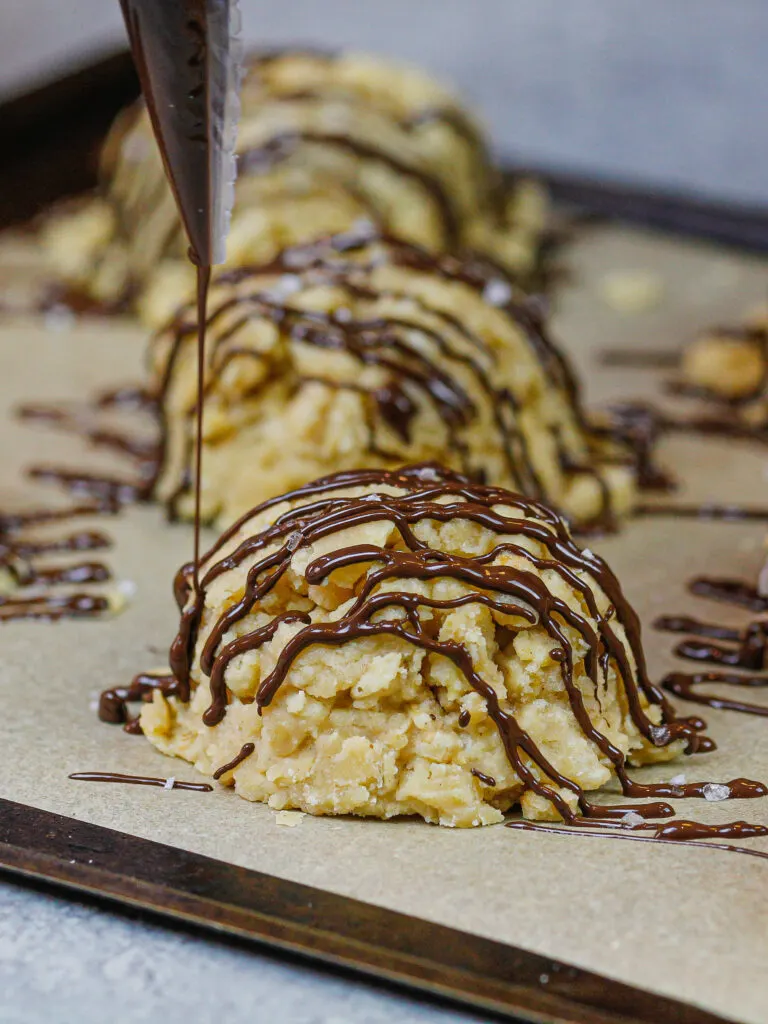 image of gluten free no bake cookies being drizzled with dark chocolate that's shared as part of a no bake recipe round up