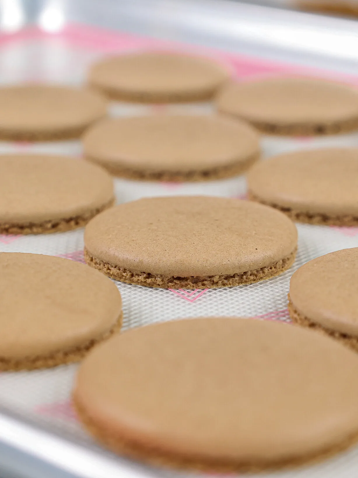image of baked chocolate macaron shells that are cooling on a silpat mat