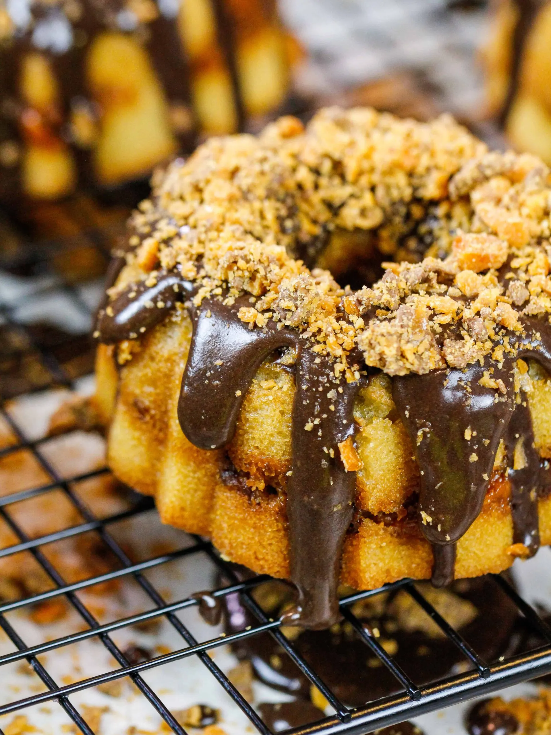 image of a mini butterfinger bundt cake topped with a chocolate glaze and chopped up Butterfinger