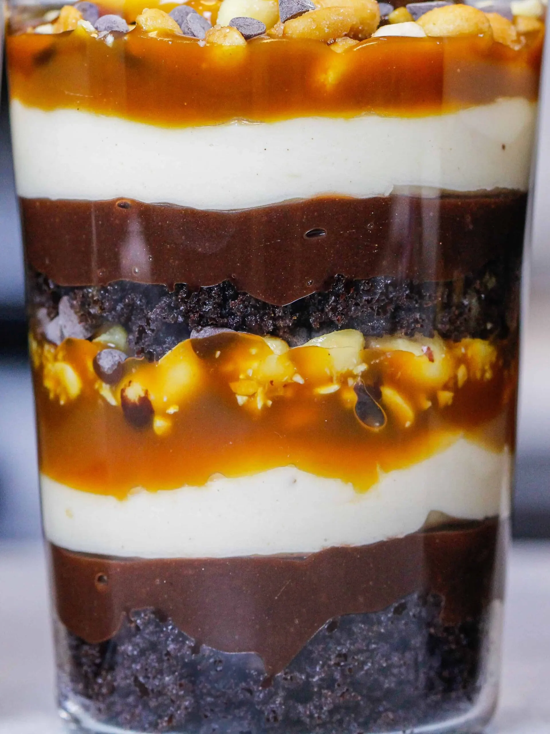 image of a snickers trifle up close showing its layers or caramel, chocolate pudding, chocolate cake, and peanut butter whipped cream