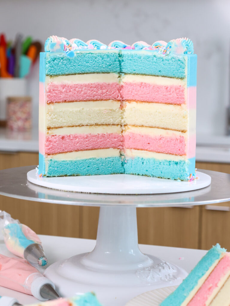 image of a cake thats been cut open with blue, pink, and white cake layers that have been stacked to look just like the trans flag