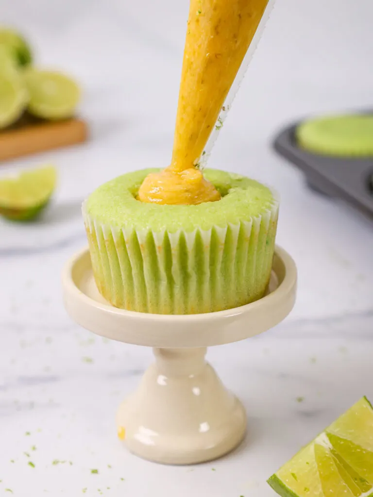 image of lime curd being piped into the center of a lime cupcake