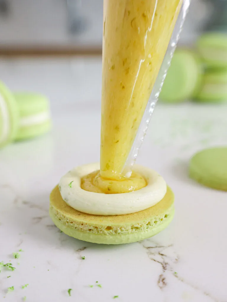 image of lime curd being piped inside of lime macarons