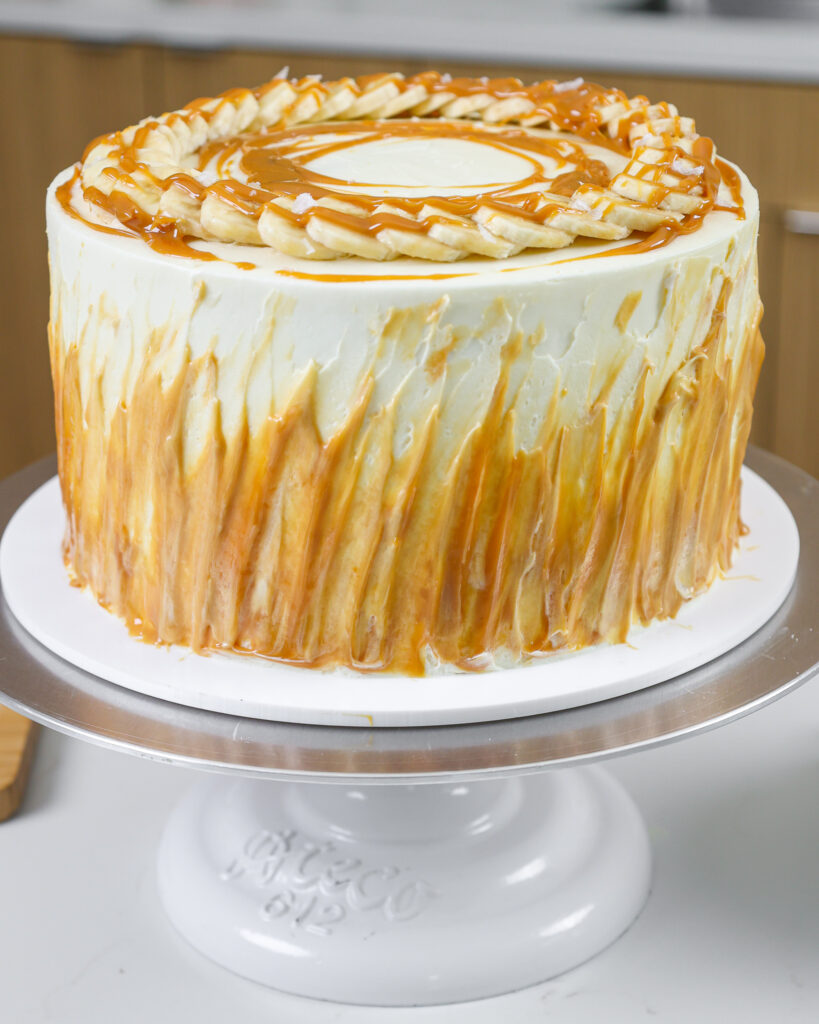 image of a banoffee layer cake that's been decorated with swipes of toffee up the side of the cake