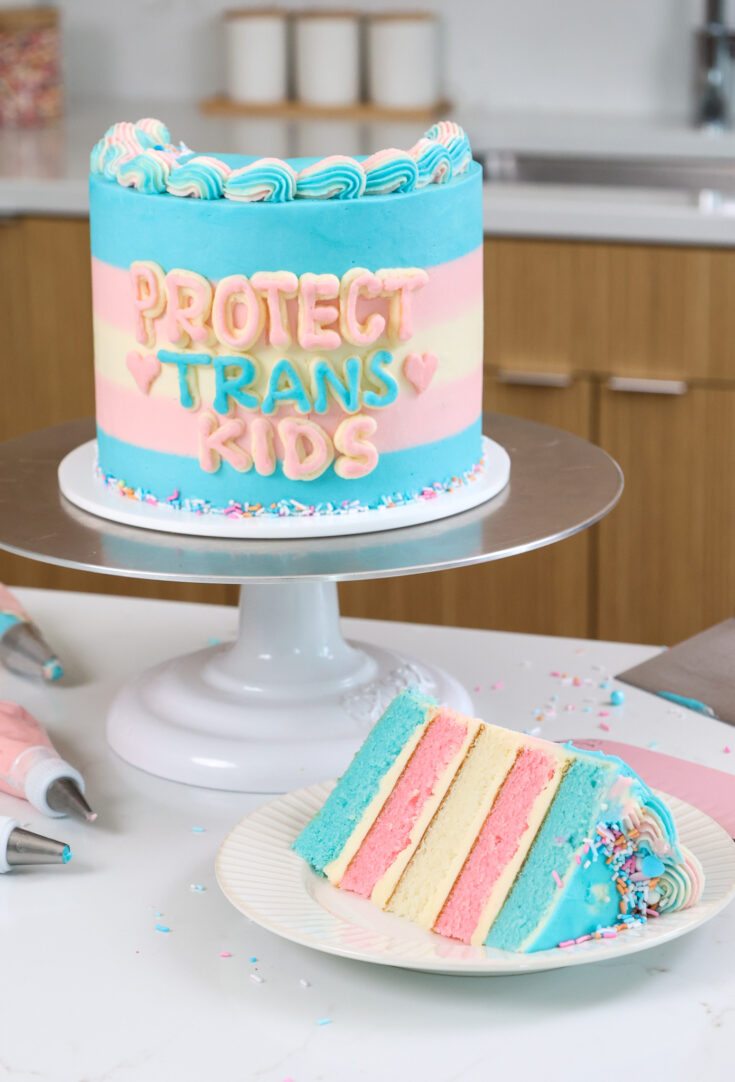 image of a trans flag cake that's been cut into to show it's cake layers that match the trans flag