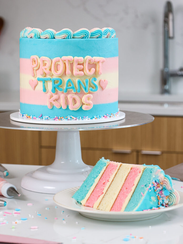 image of a trans flag cake that's been cut into to show it's cake layers that match the trans flag