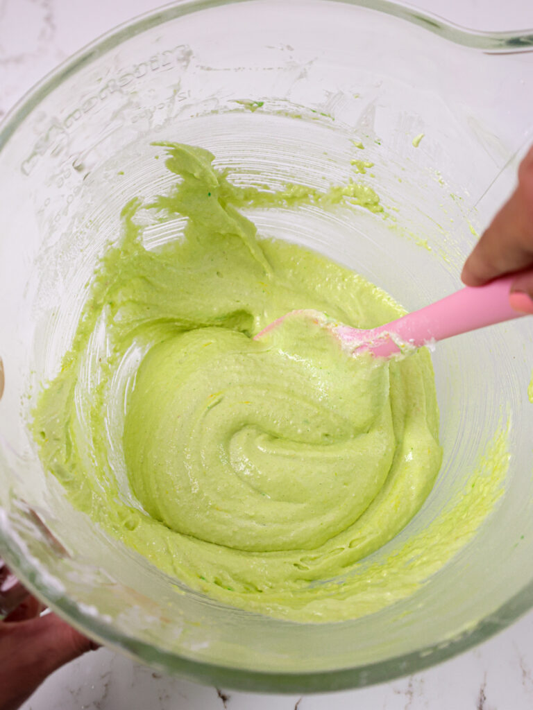 image of bright green macaron batter being mixed with a rubber spatula