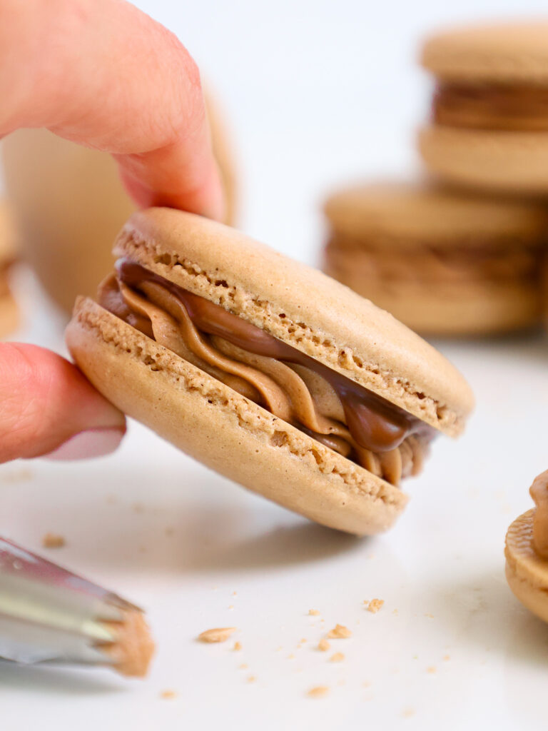 image of a Nutella macaron that's being held up to show its delicious Nutella buttercream filling