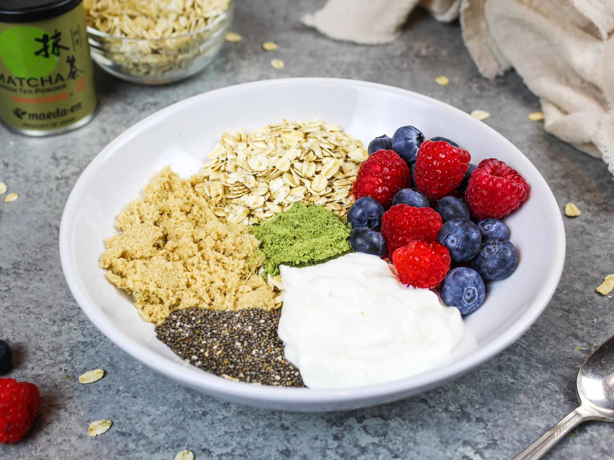 image of ingredients in a bowl to make overnight oats with chia seeds, greek yogurt, brown sugar, berries, honey and old fashioned oats