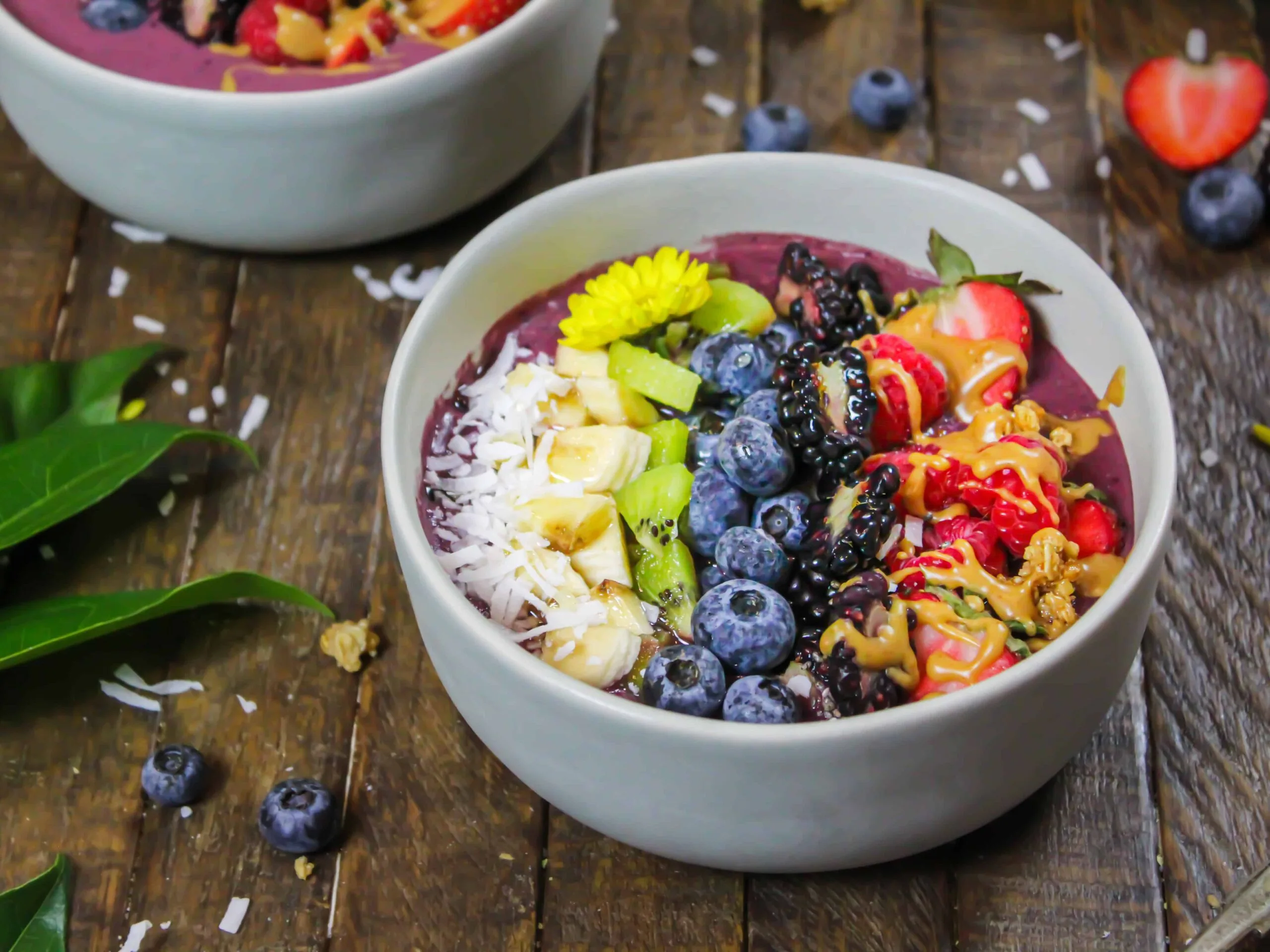 image of an acai bowl made with peanut butter and decorate with fresh fruit, granola, and some edible flowers