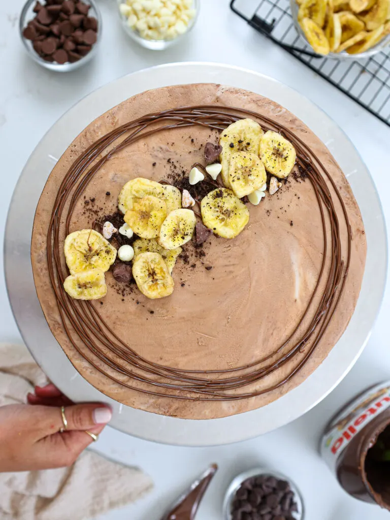 image of a nutella banana cake that's been decorated with a swirl of Nutella and banana chips