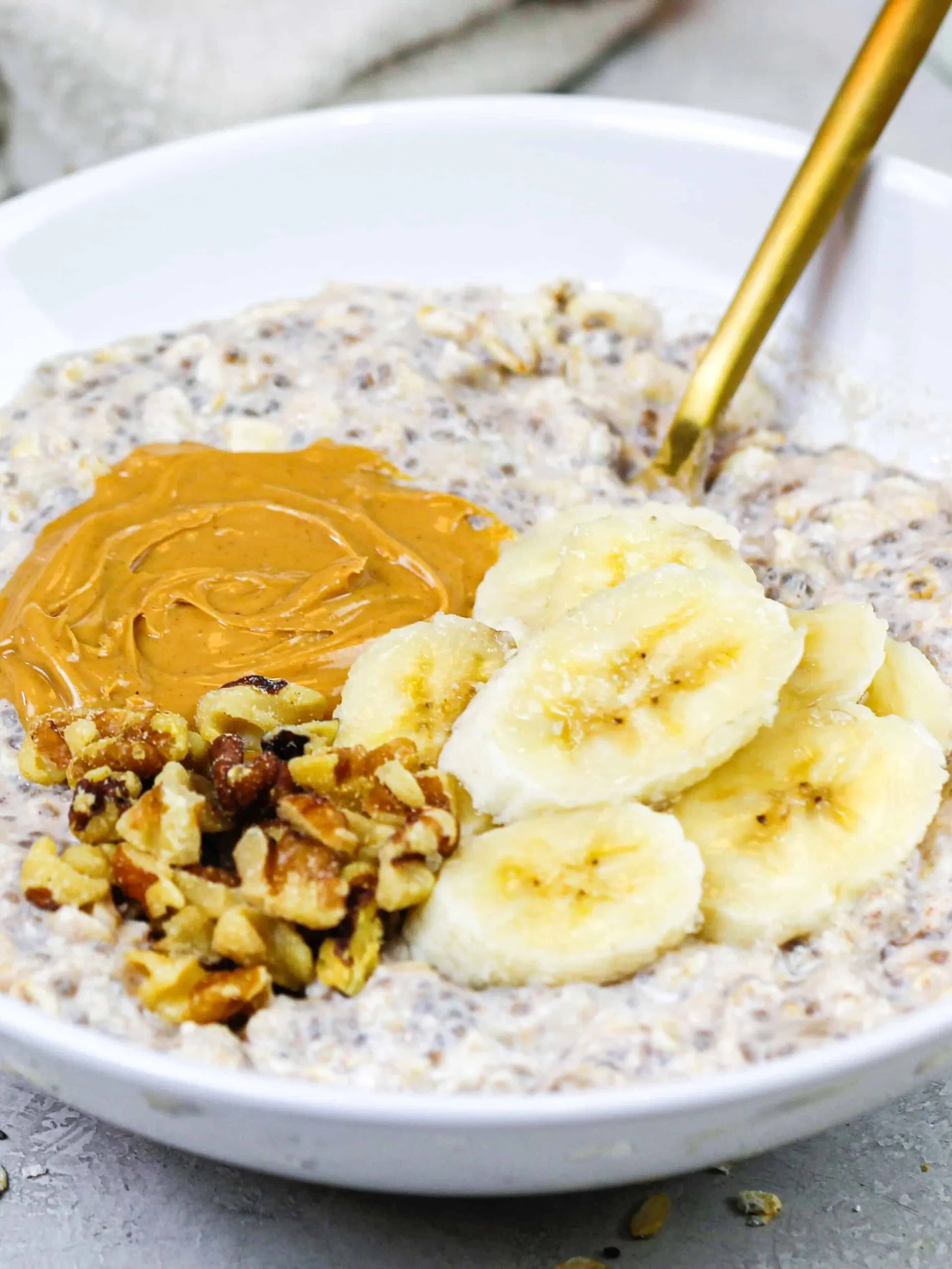 image of banana overnight oats in a bowl topped with peanut butter and chopped nuts