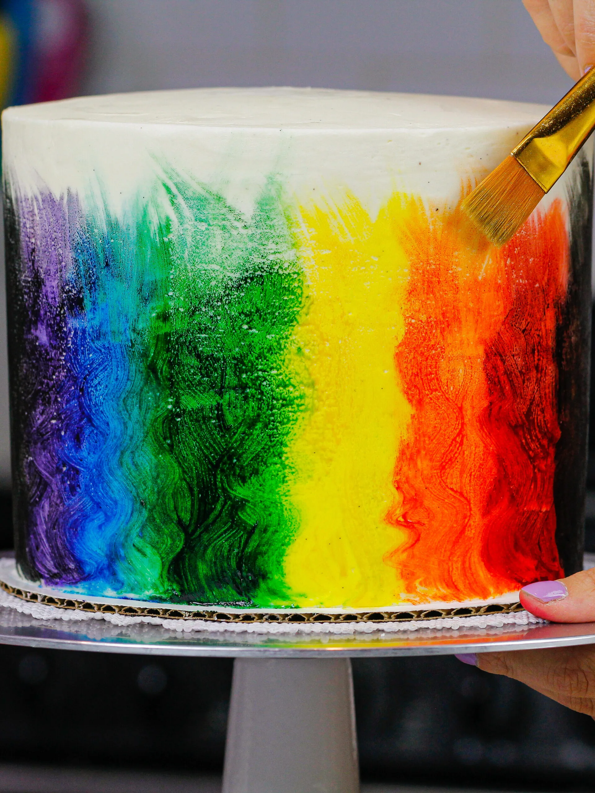 image of pride cake being painted rainbow colors with edible paint made from vodka and gel food coloring.