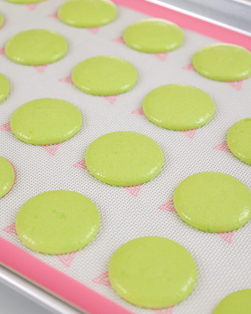image of green macaron shells that have been piped and are resting