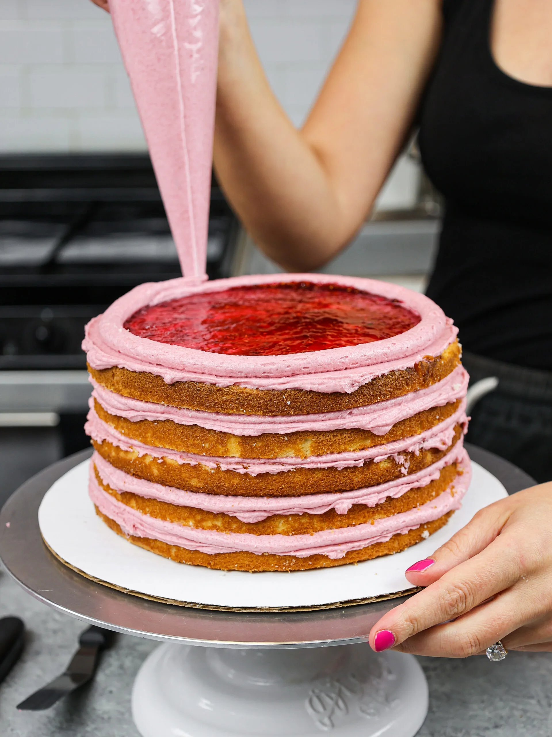 image of a cake being filled with raspberry jam surrounded by a frosting ring