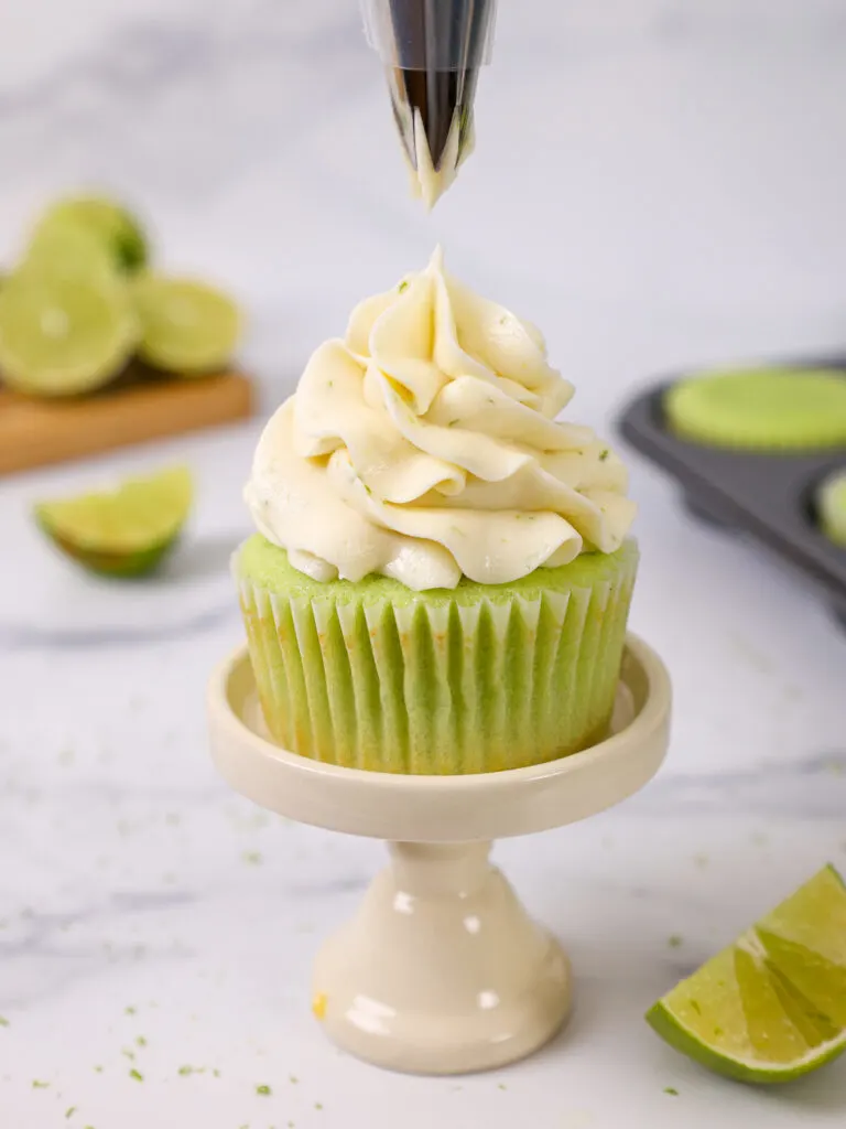 image of lime buttercream being piped on top of a lime cupcake