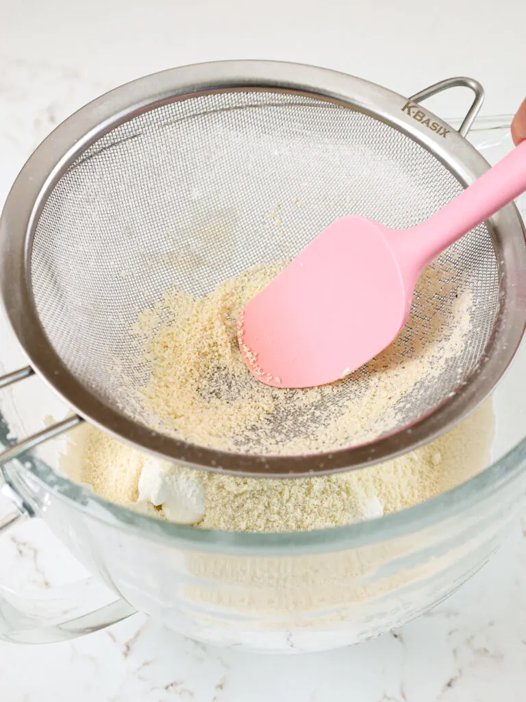 image of dry ingredients being pushed through a sieve to make macaron shells