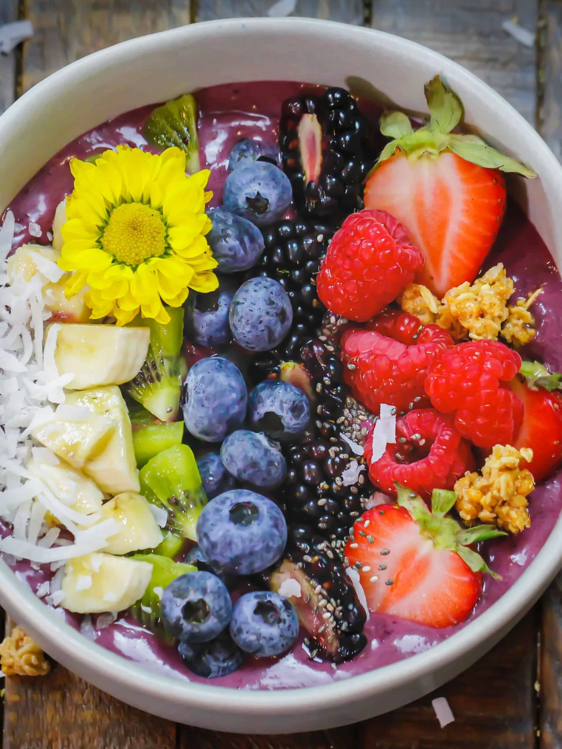 image of a pretty acai bowl topped with coconut, chia seeds, bananas, strawberries, kiwi, blueberries, strawberries and blackberries 