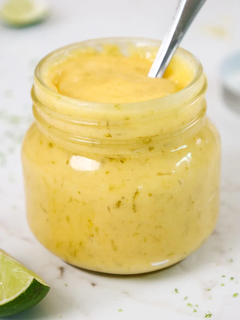 image of lime curd that's been scooped into a glass jar for easy storage
