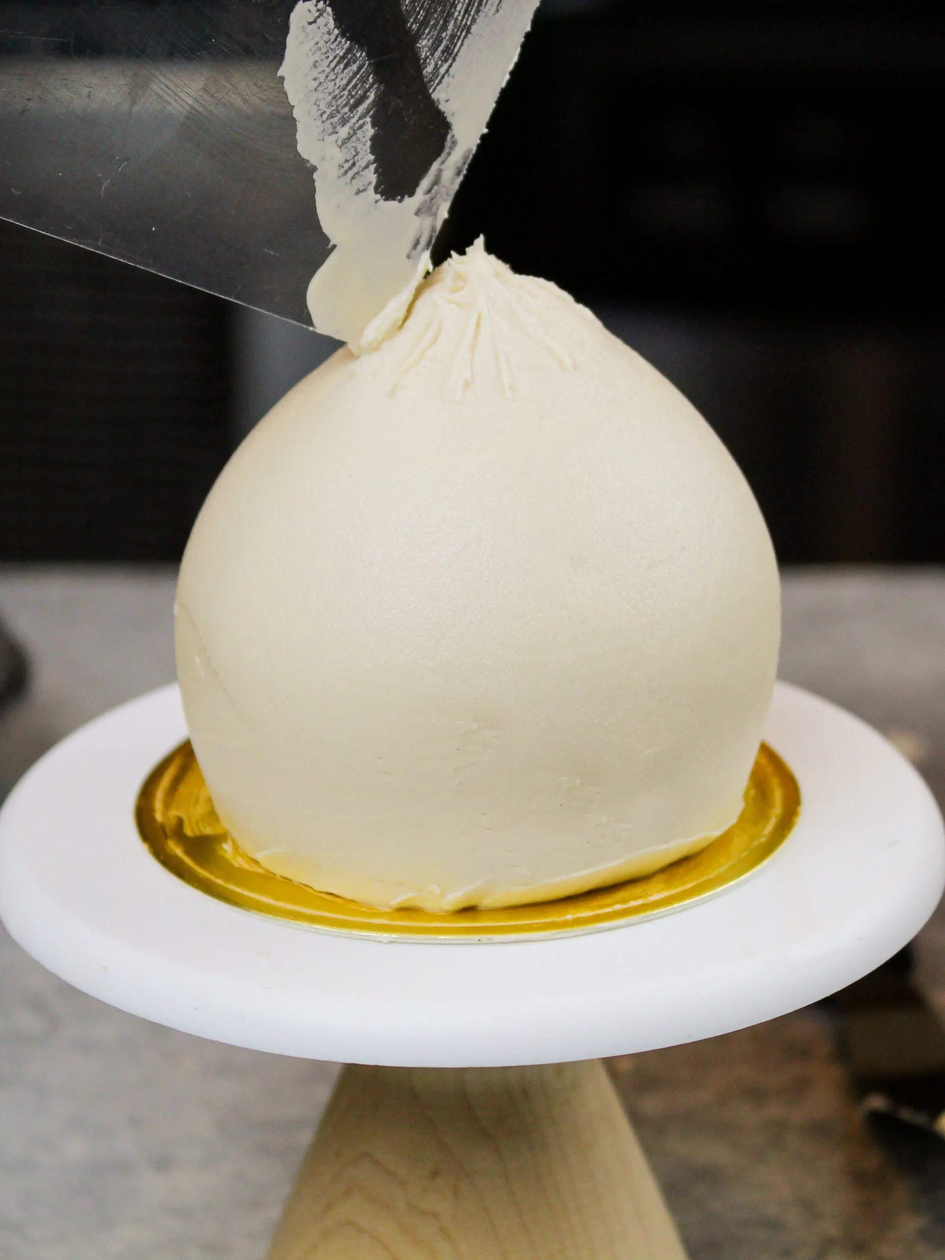 image of a dumpling cupcake being decorated with frosting and smoothed using an acetate sheet