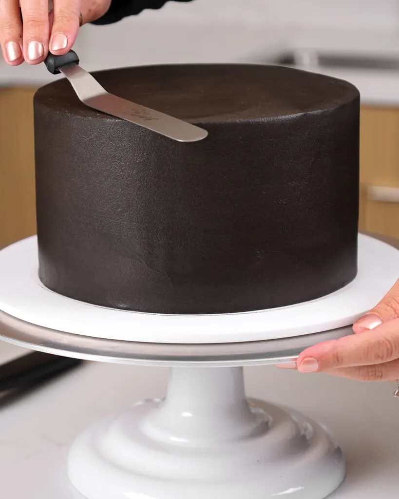 image of black buttercream frosting being smoothed onto a black velvet cake