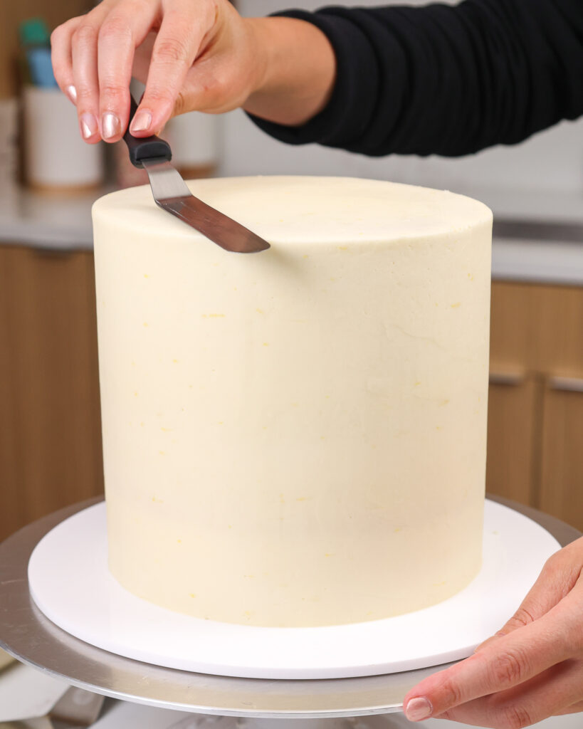 image of a white chocolate raspberry lemon cake that's being frosted with white chocolate buttercream