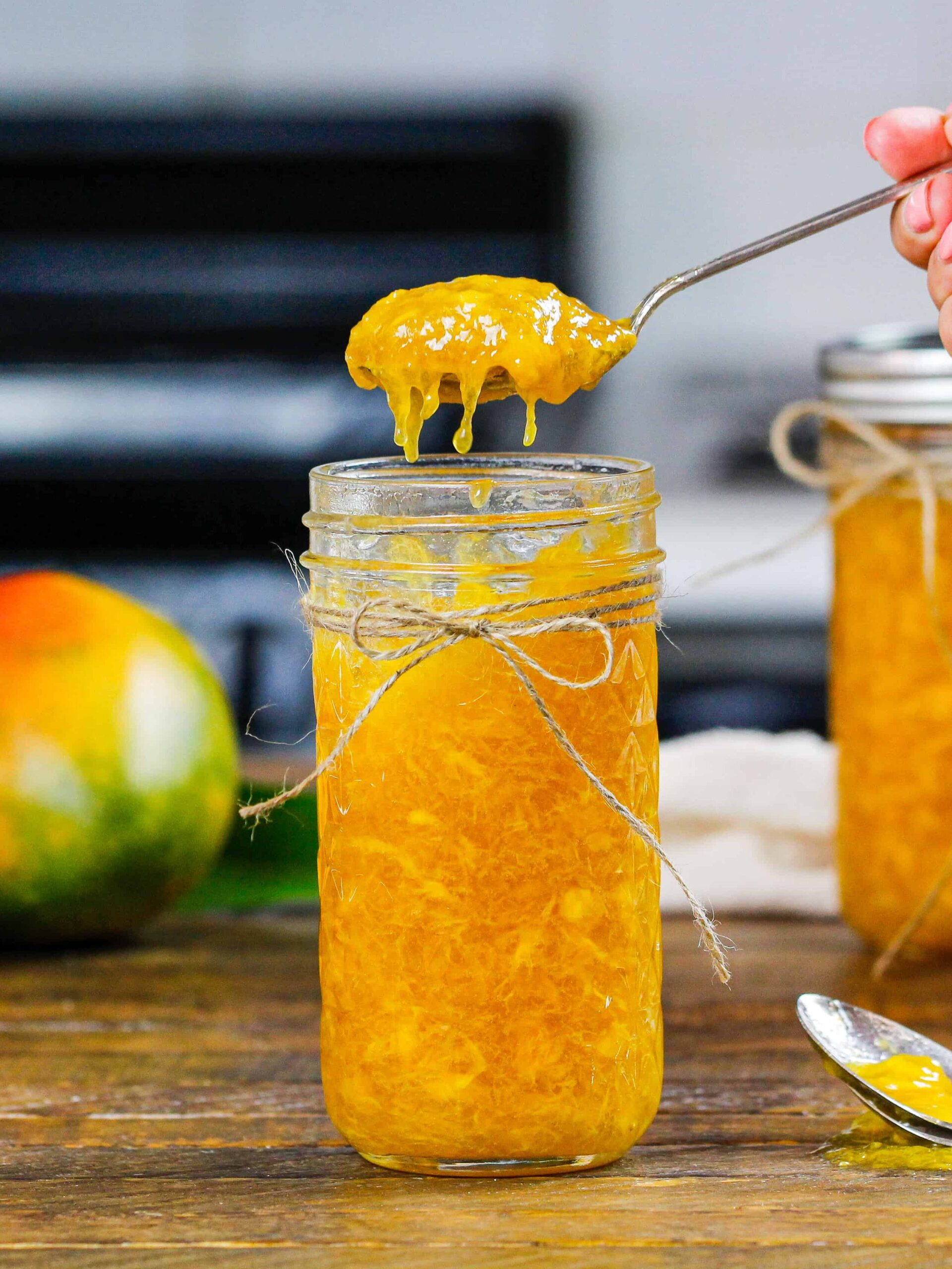 image of mango freezer jam being spooned out of a mason jar