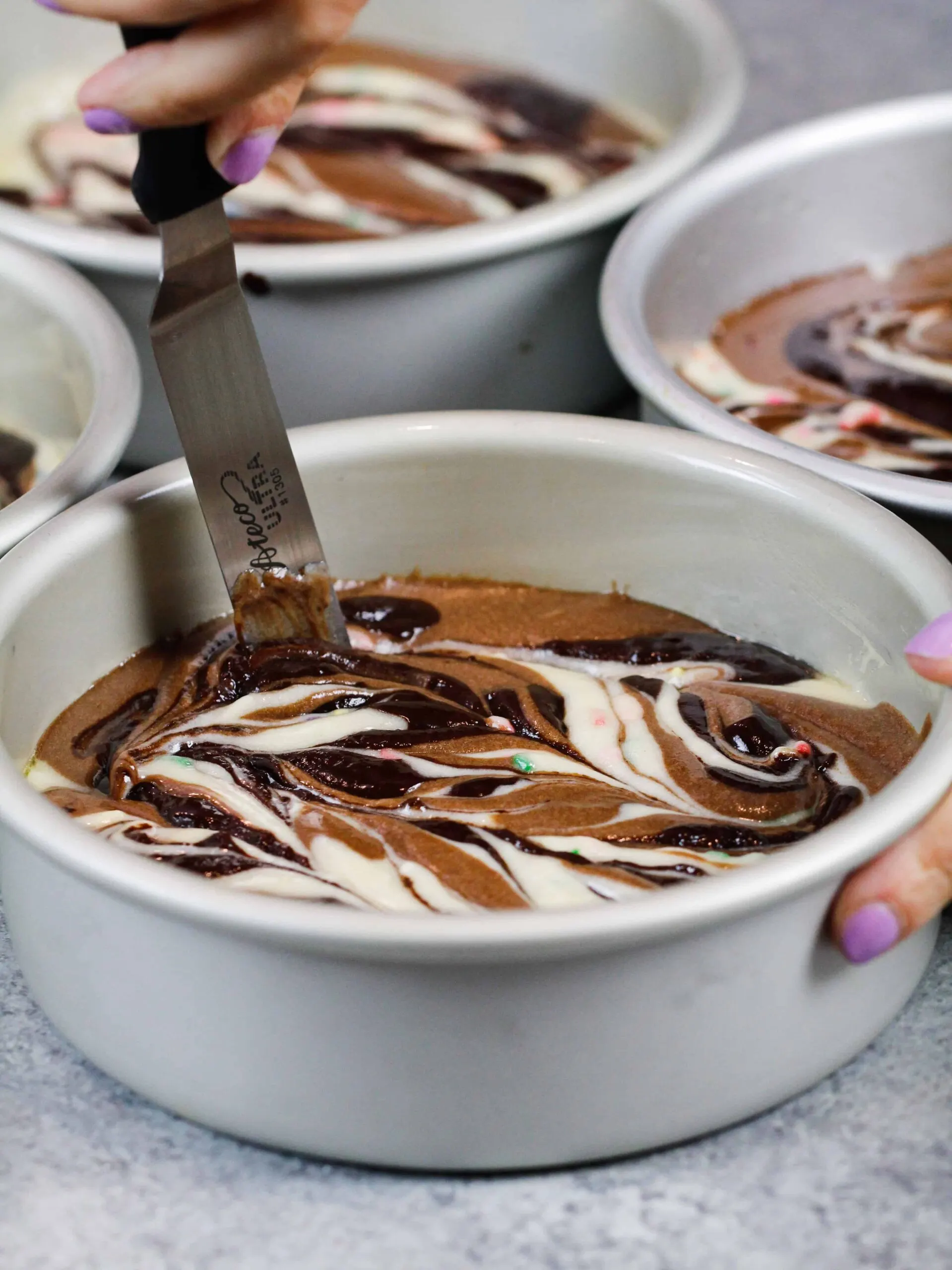 image of chocolate and vanilla cake batter being swirled to make marble cake layers