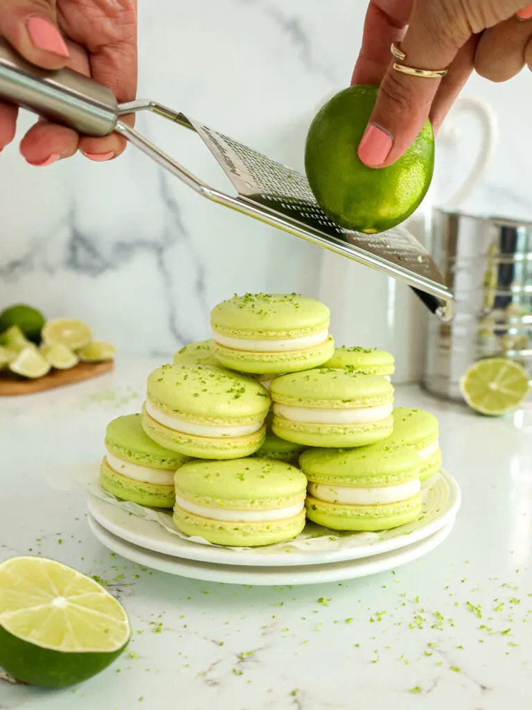 image of a stack of lime macarons that are being topped with fresh lime zest