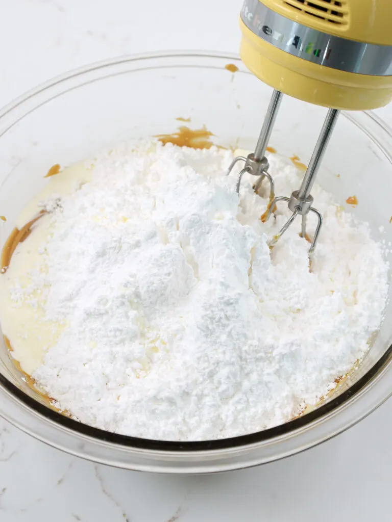 image of powdered sugar being mixed into butter, cream cheese and peanut butter to make peanut butter cream cheese buttercream frosting