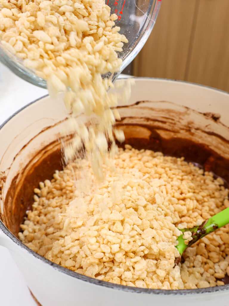 image of rice krispie cereal being poured into a chocolate butter mixture