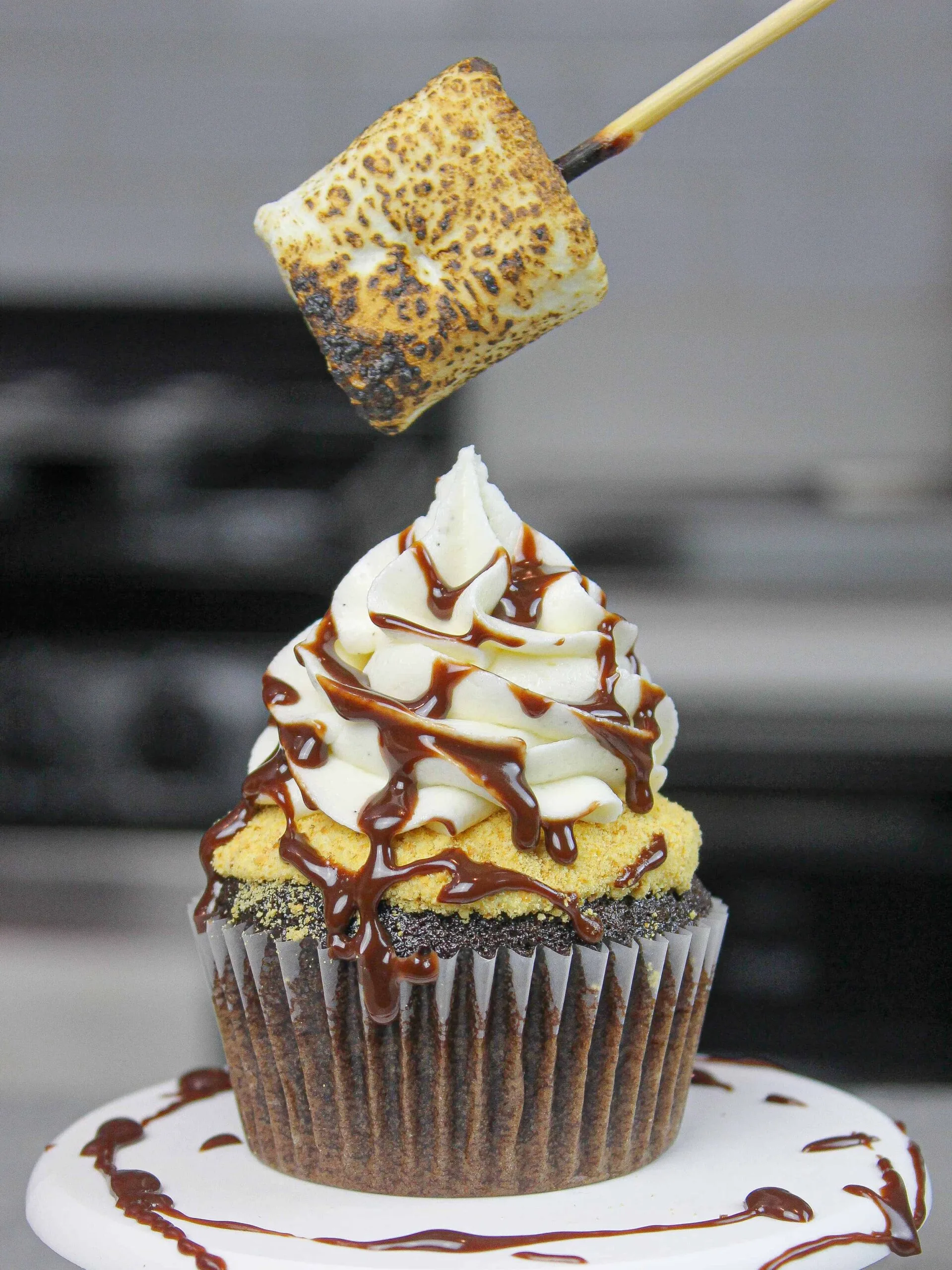 image of a toasted marshmallow being added on top of a s'mores cupcake