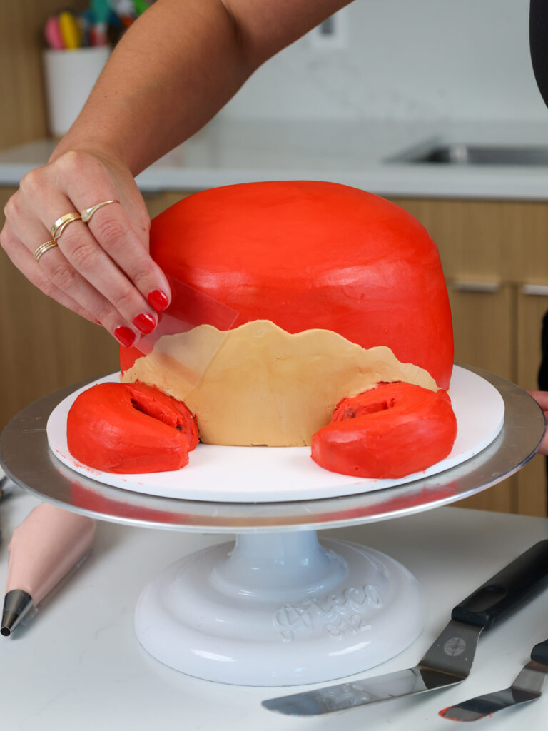 image of tan frosting being smoothed onto a cute crab cake to make its belly