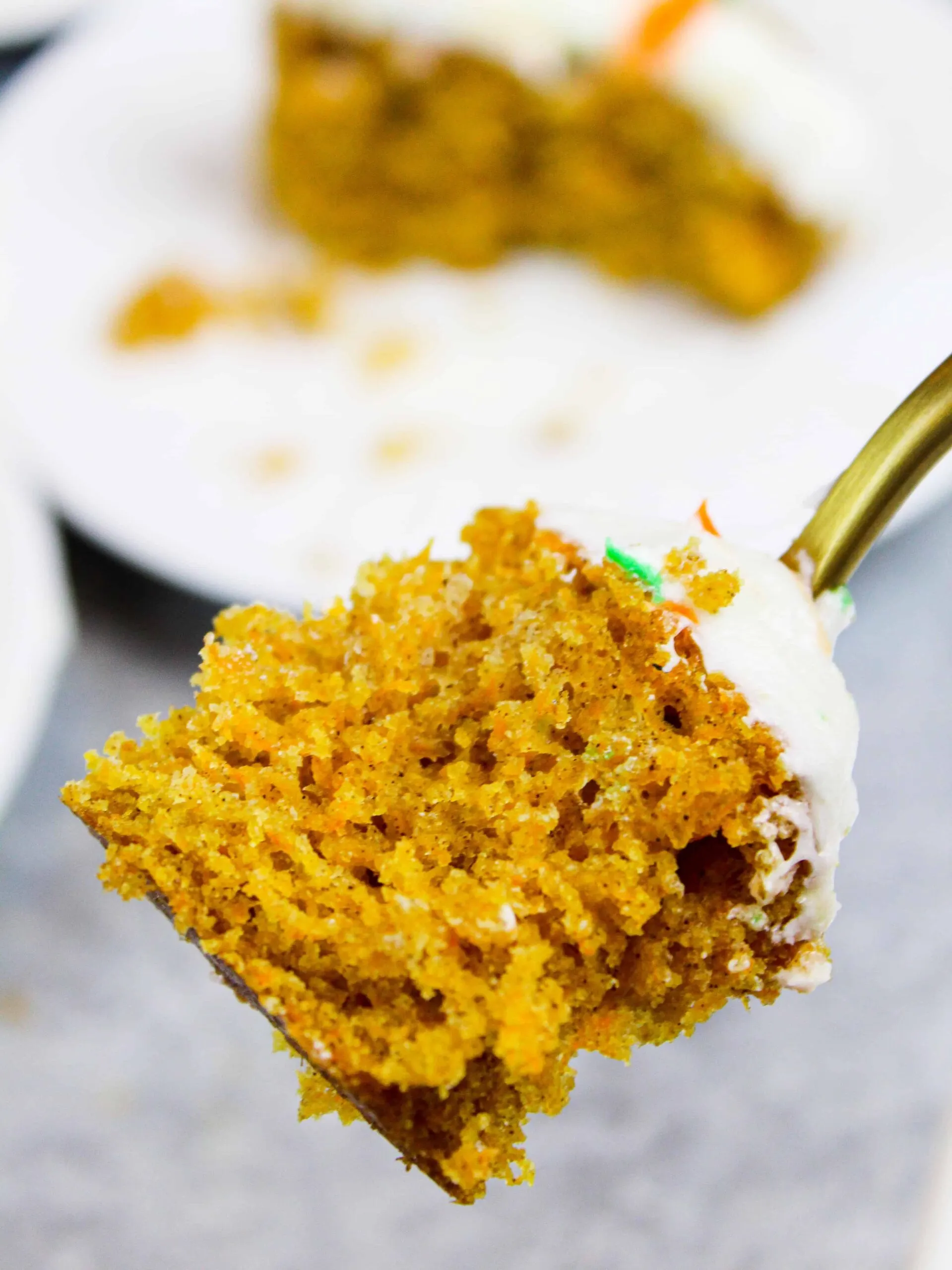 image of a bite of carrot cake sheet cake on a fork with the slice behind it