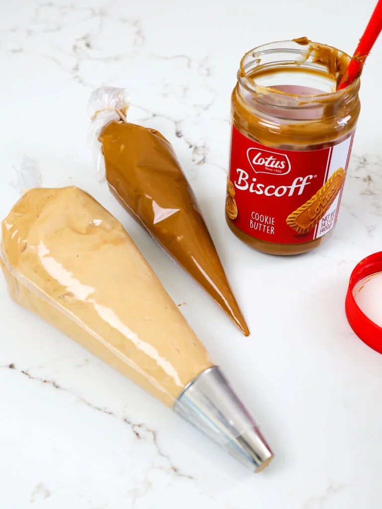 image of biscoff buttercream and cookie butter in piping bags that are ready to be used to fill biscoff macarons