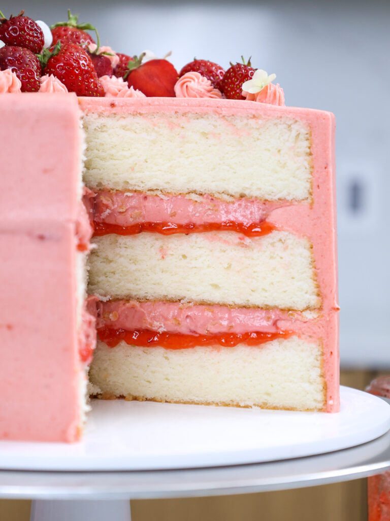 image of a fluffy white cake that's been filled with strawberry mousse, strawberry jam, and frosted with strawberry buttercream