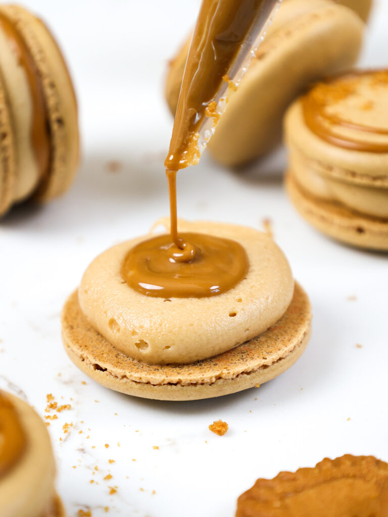 image of a biscoff macaron being filled with cookie butter
