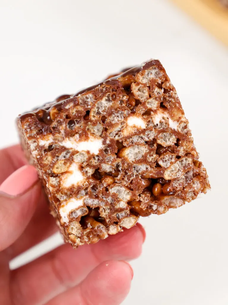 image of a chocolate rice krispie treat being held up to show it's chewy texture