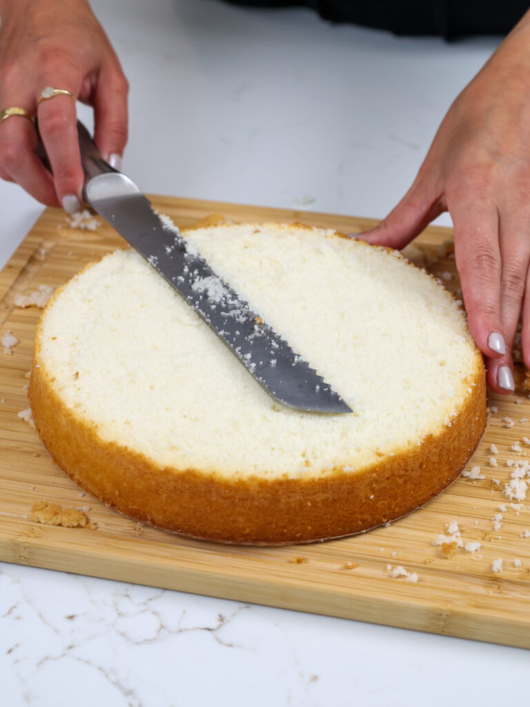 image of a fluffy white cake later being leveled with a serrated knife