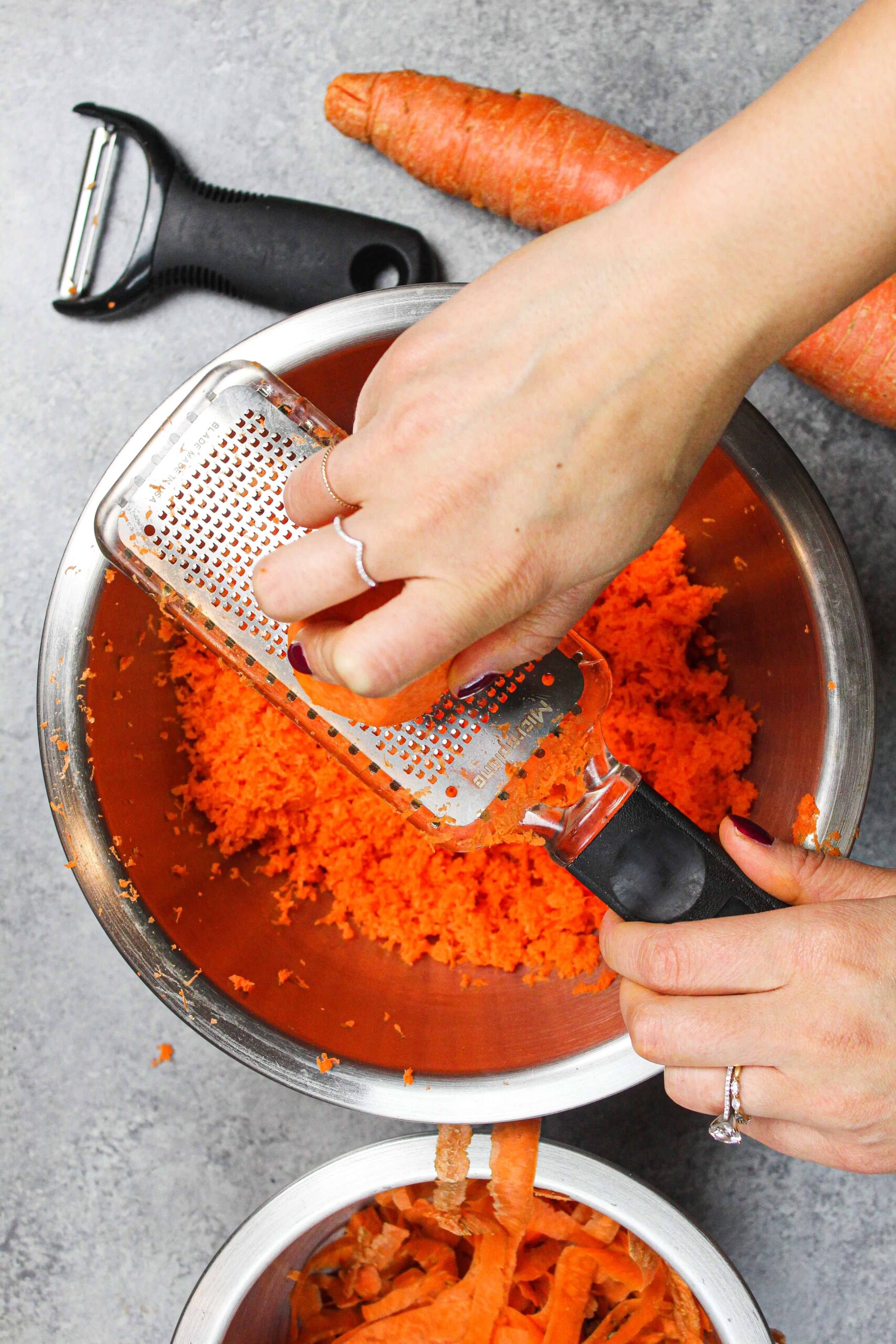 image of carrots being grated on a microplane grater for carrot cake recipe
