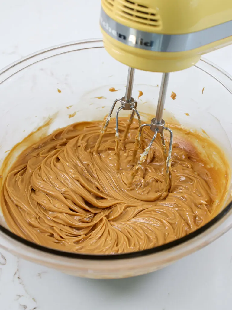 image of butter and lotus biscoff cookie butter being mixed together with a yellow hand mixer