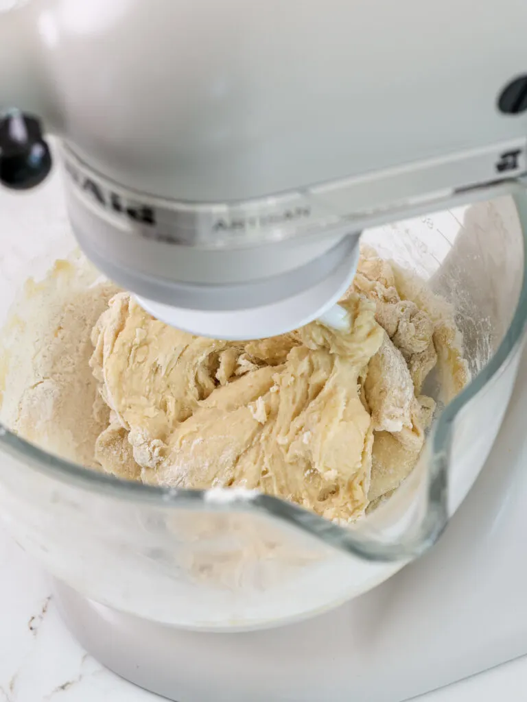 image of cinnamon roll dough being mixed in a kitchen aid mixer with a dough hook